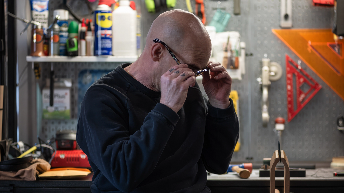 Ryan Price putting on his glasses in front of a pegboard tool wall in the L'officina di LeRoy workshop