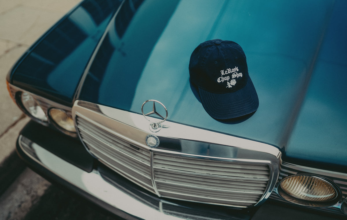 Navy LeRoy's Chop Shop cap resting on the hood of a blue classic Mercedes-Benz