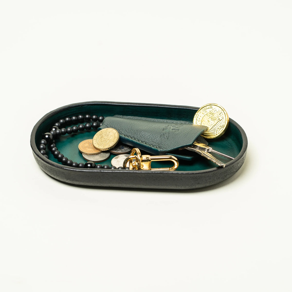 Vessel valet tray holding coins, keys, and a Key Coffin key fob