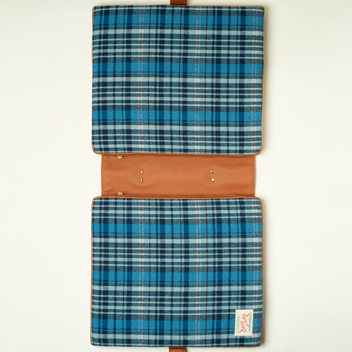 Tartan tailgate cushion in use on a wooden surface