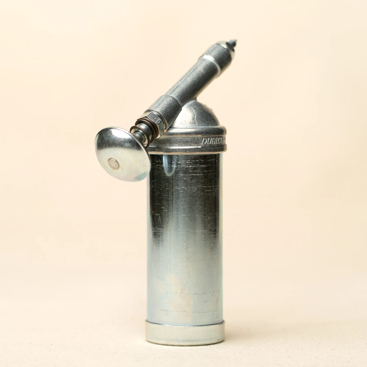 L'officina x Dualco mini grease gun top-down view on a beige background
