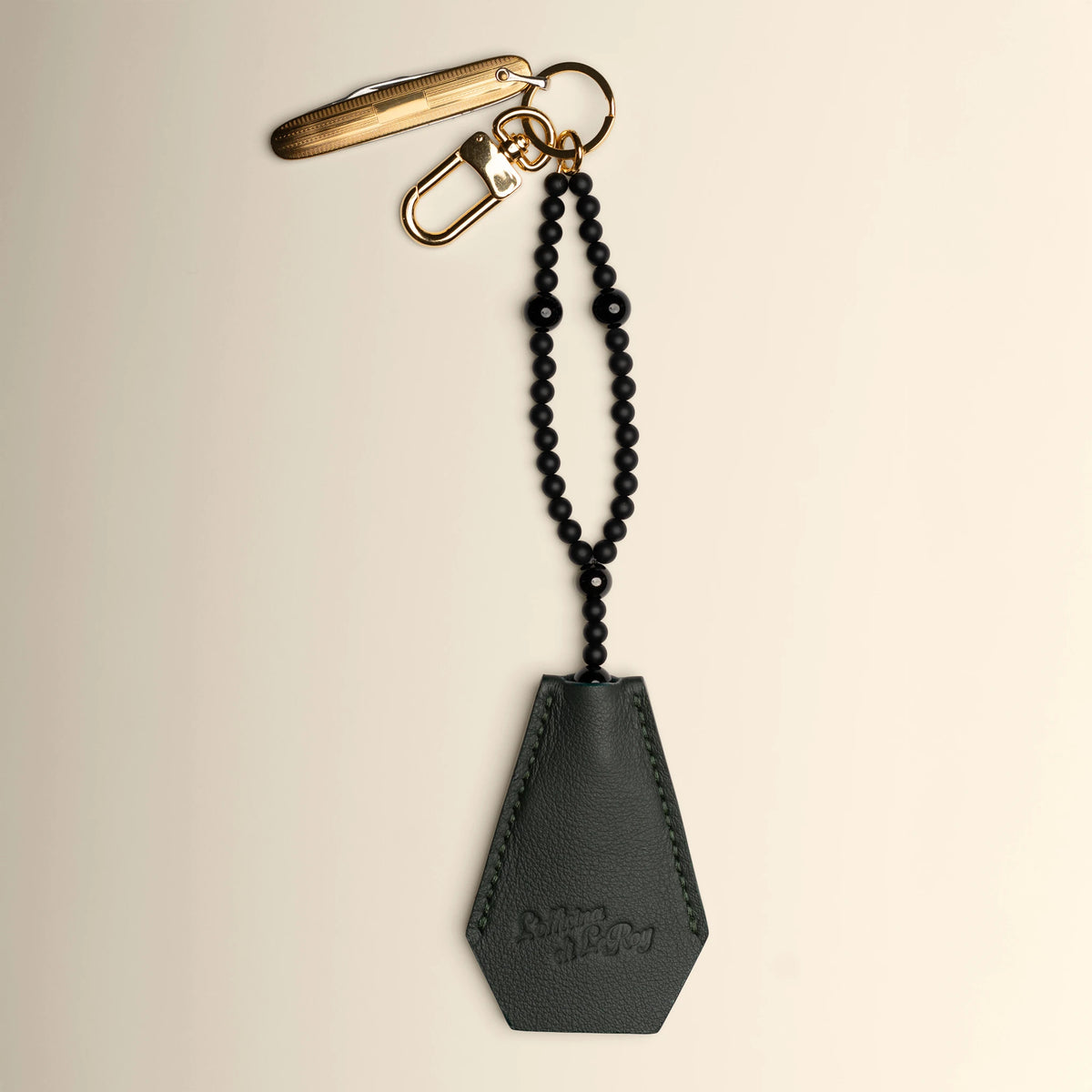 Key Coffin in onyx black leather with brass ring on a beige background