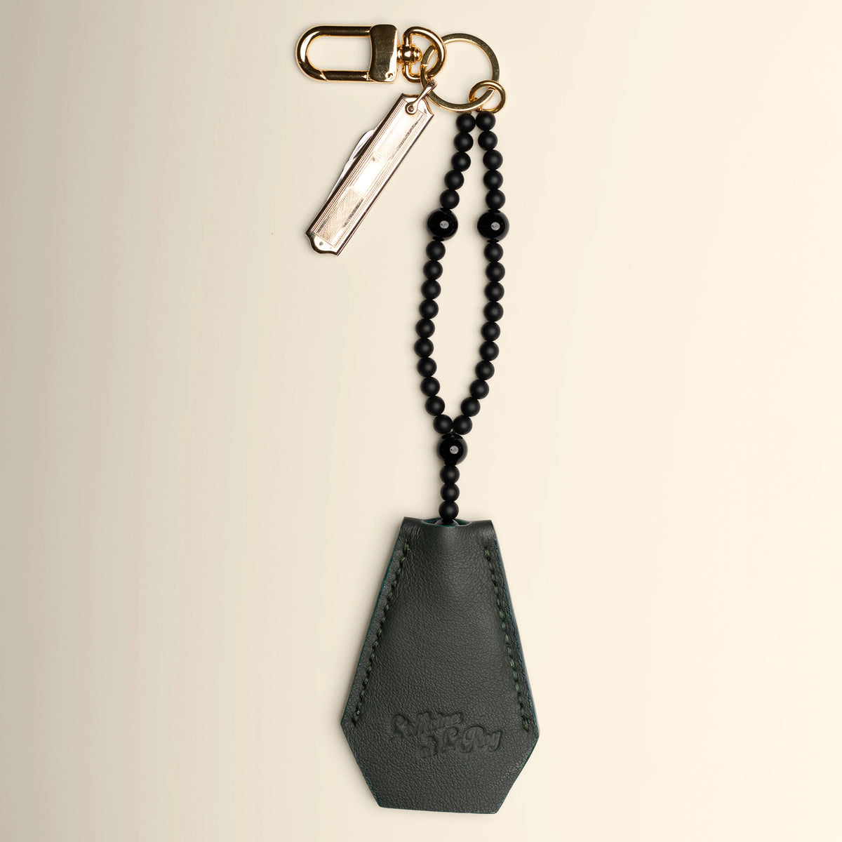 Key Coffin in tan leather with brass ring on a beige background