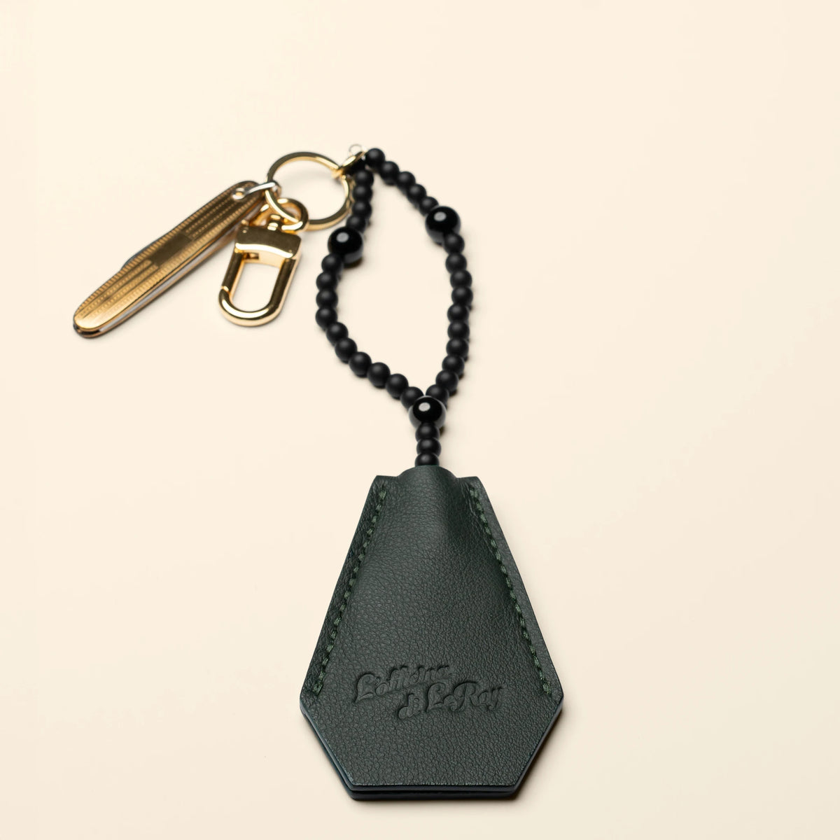 Key Coffin leather key fob, angled flat lay on a beige background