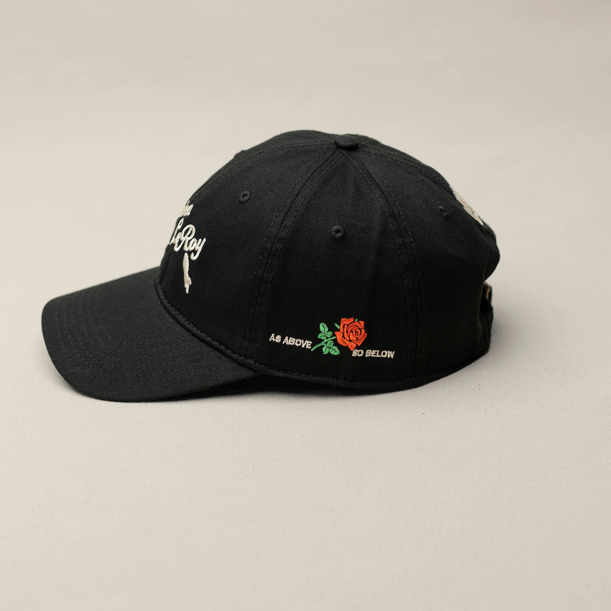 Close-up of As Above So Below embroidered rose and text on black low-profile cap